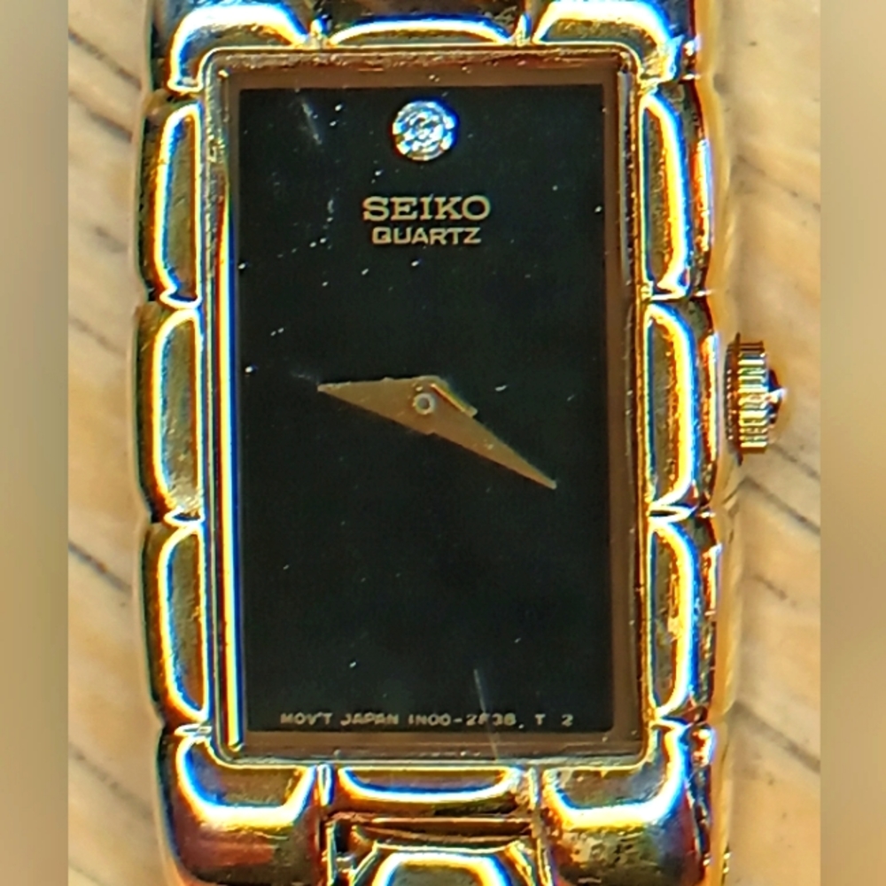 Seiko Ladies Black dial, 2 hand movement gold case and bracelet w/diamond at 12